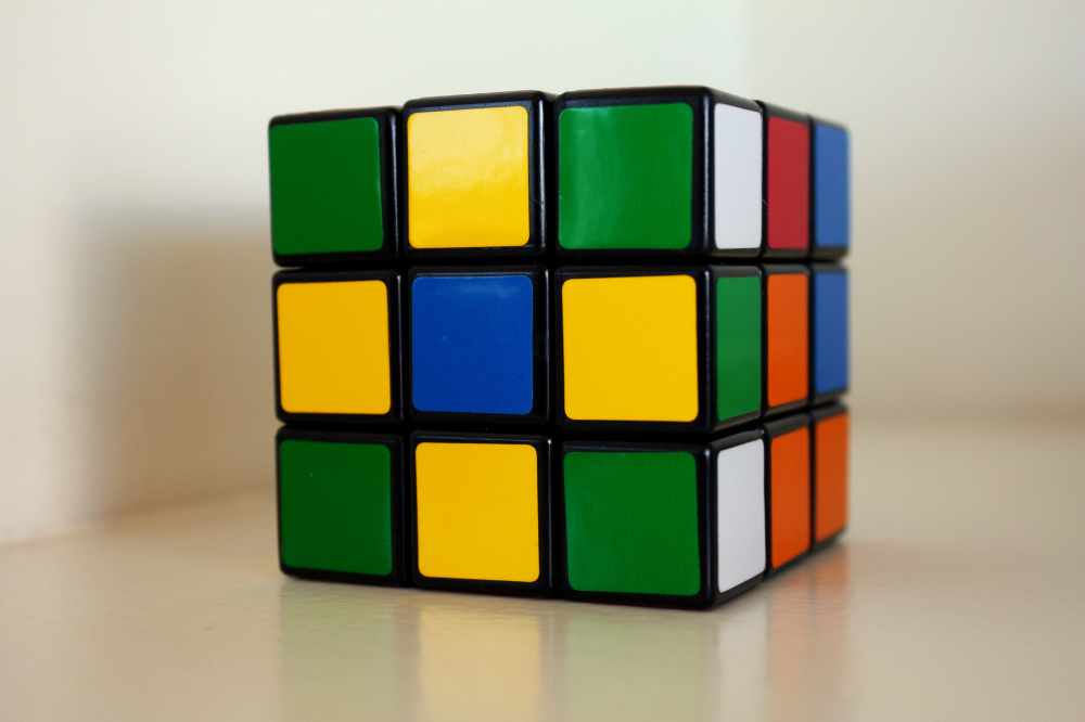 A partially solved Rubik’s Cube sits on a light surface.