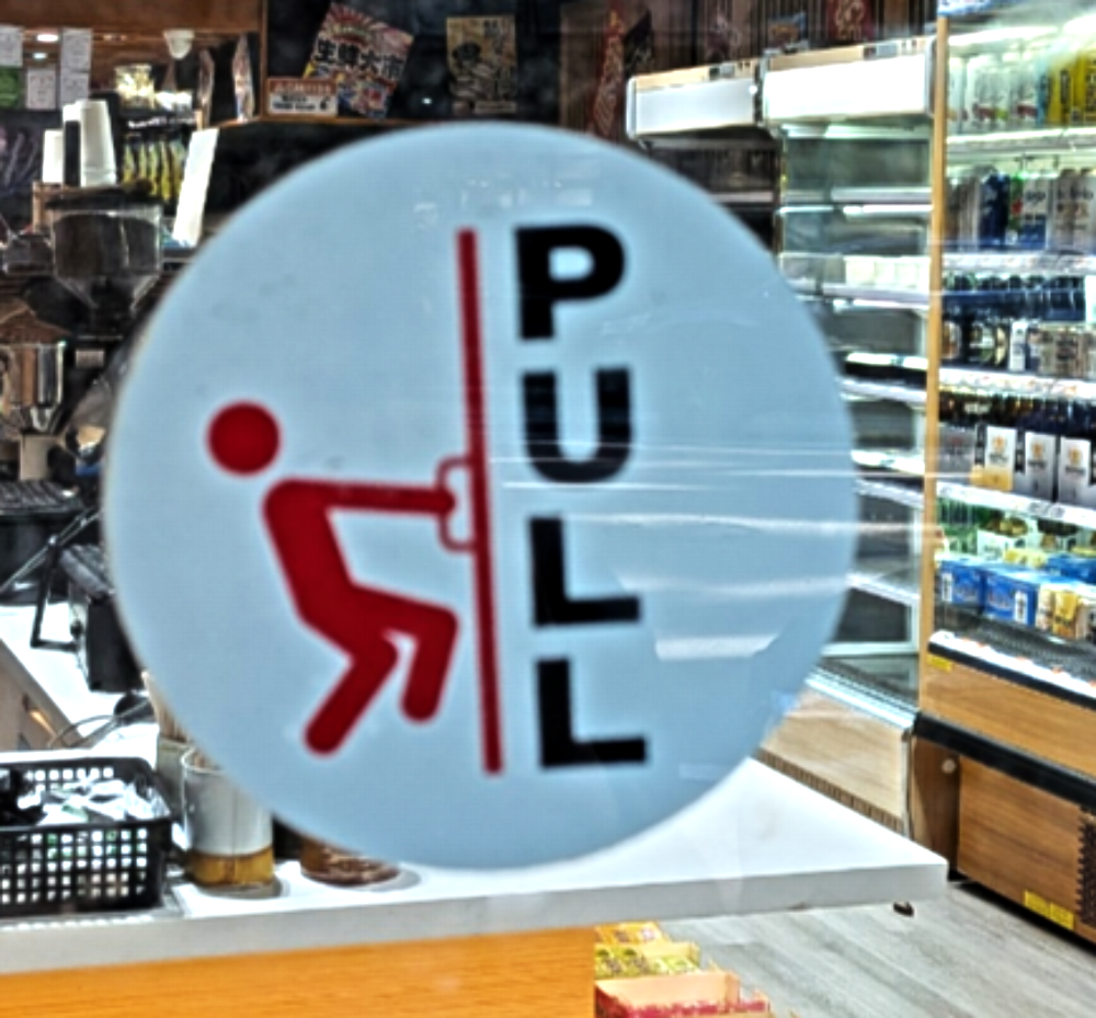 A round “Pull” door sticker featuring an icon of a red figure pulling a door.