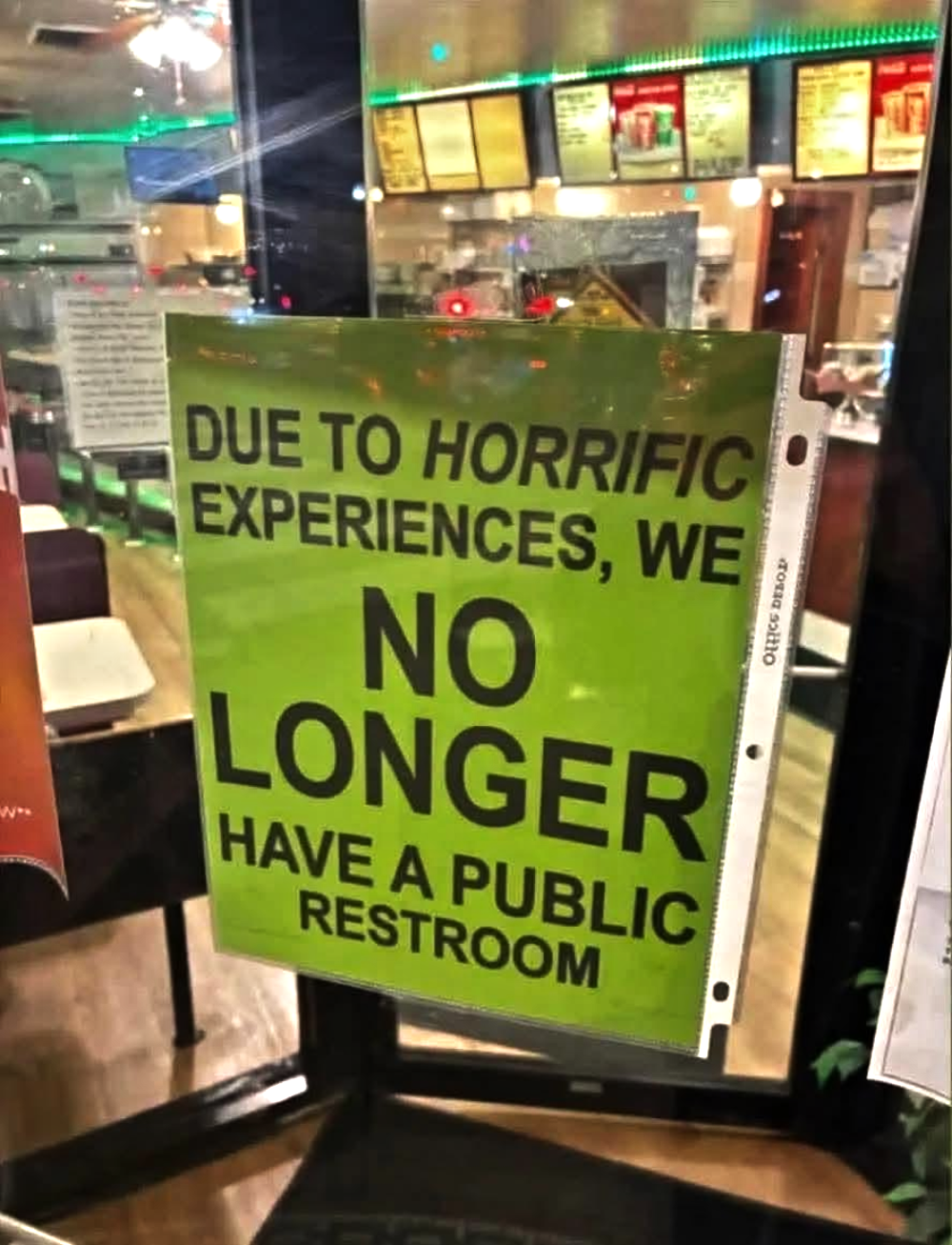 A sign in a restaurant window stating, “Due to horrific experiences, we no longer have a public restroom.”