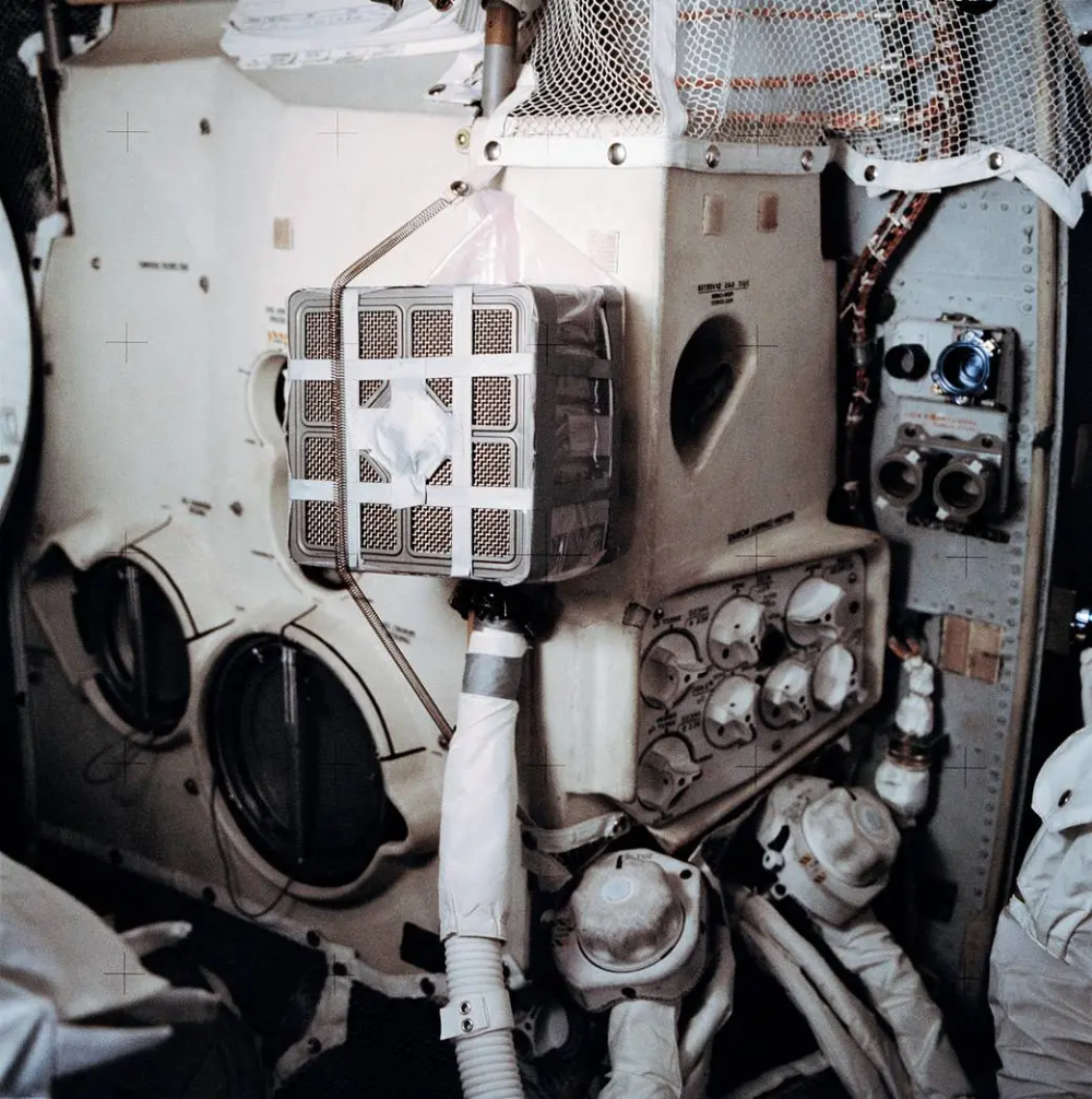 An Apollo command module environmental control system panel featuring dials, switches, and a lithium hydroxide canister used for carbon dioxide removal.