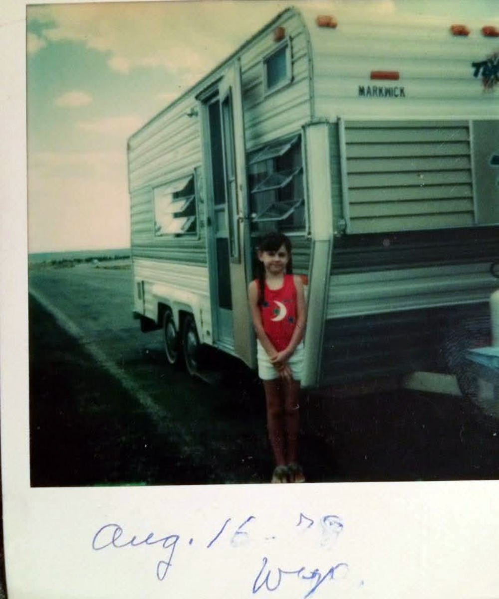A young girl stands in front of a Markwick travel trailer in a vintage photo dated August 16, 1989.