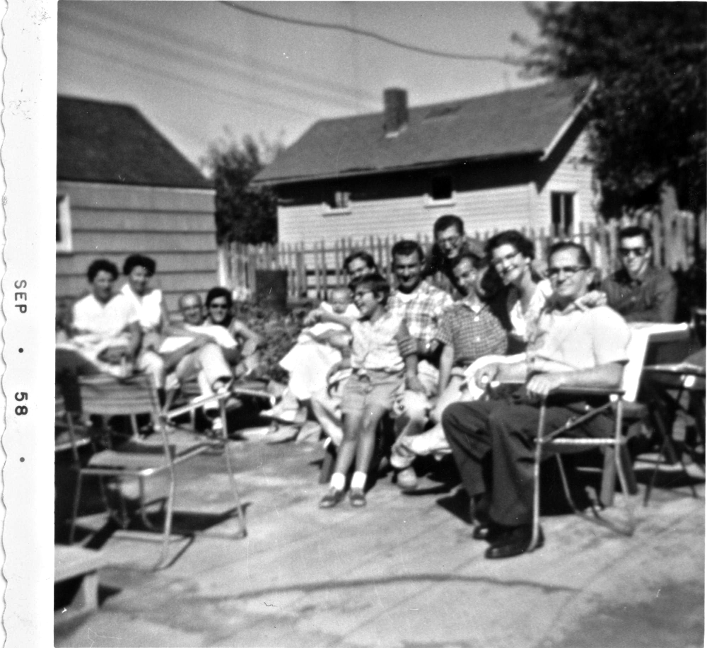 A large group of people posing for a photograph in a backyard, dated September 1958.