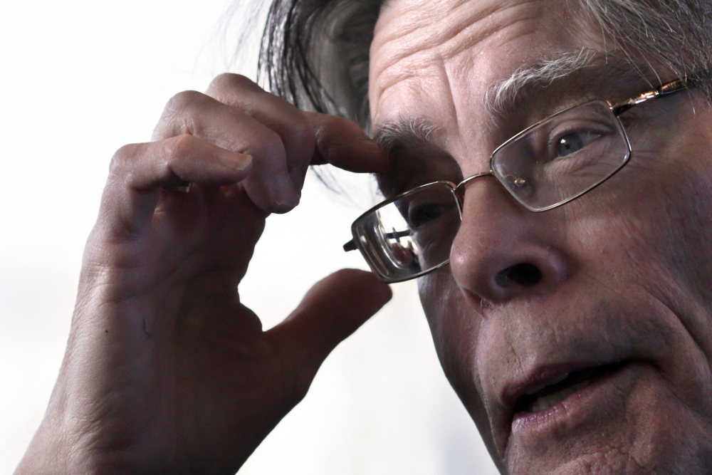 Close-up portrait of author Stephen King with his hand held to his forehead.