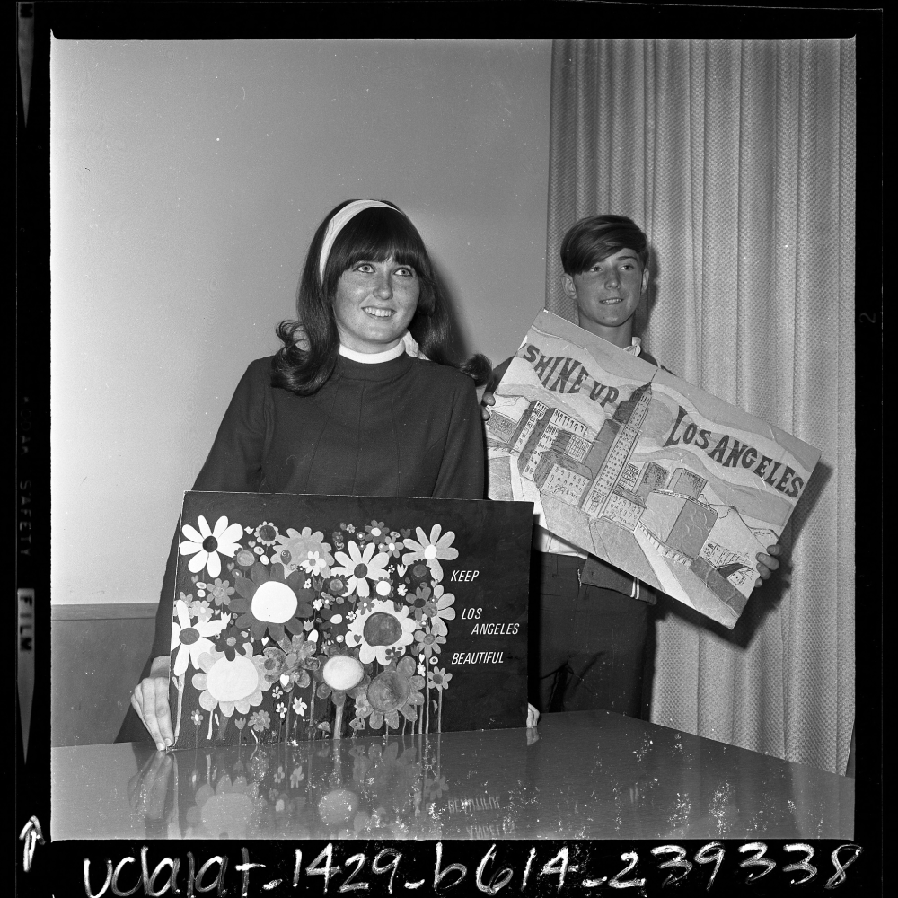 A young woman and man holding posters that read “Keep Los Angeles Beautiful” and “Shine Up Los Angeles.”