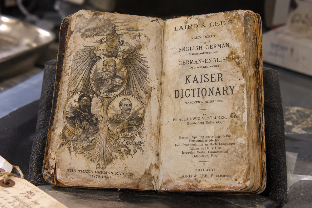 An open, antique “Laird & Lee’s Vest-Pocket English-German German-English Kaiser Dictionary” showing a portrait page of three German Kaisers on the left and the title page on the right.