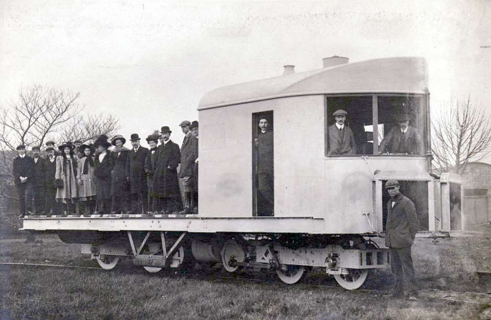 A group of people standing on and beside a large, streamlined experimental railway carriage.