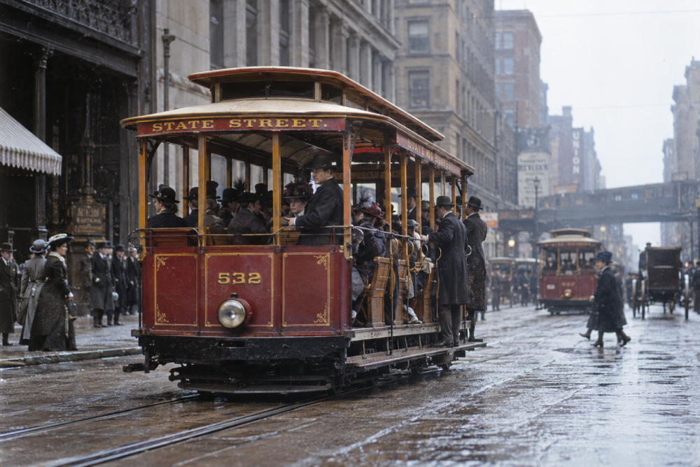 A red State Street cable car filled with passengers travels down a rainy city street.