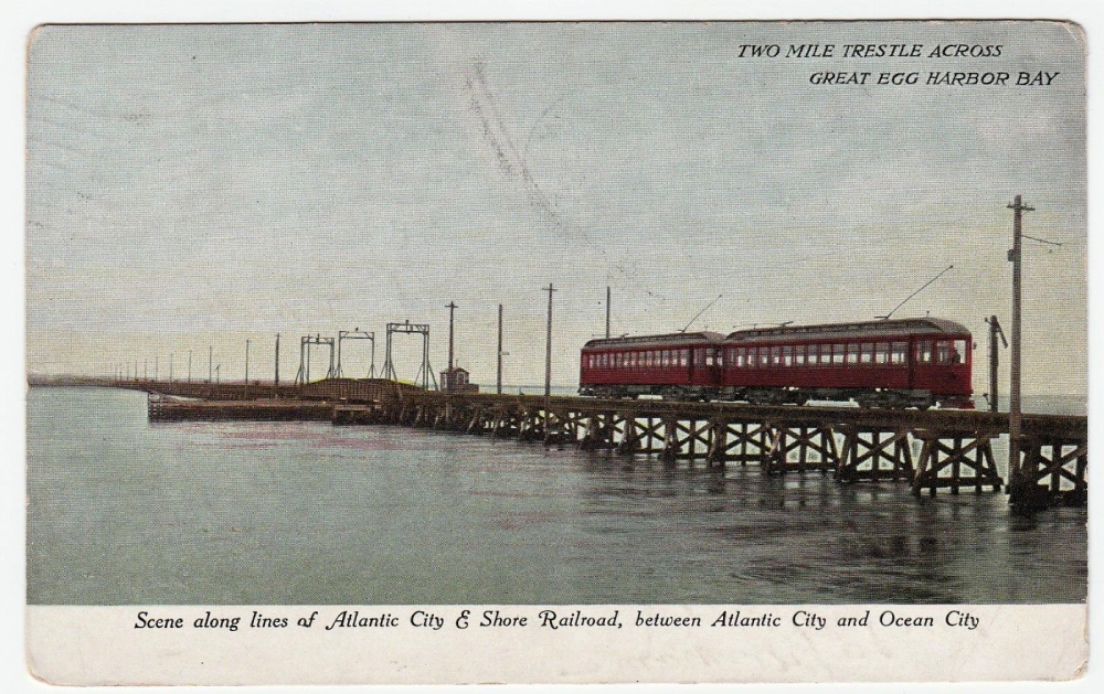 Vintage postcard of a red Atlantic City & Shore Railroad train crossing a long wooden trestle over Great Egg Harbor Bay.