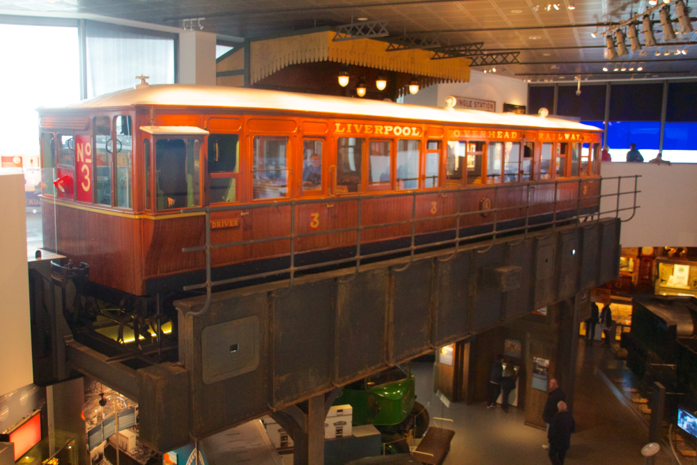 A vintage orange and brown carriage from the Liverpool Overhead Railway on display inside a museum.