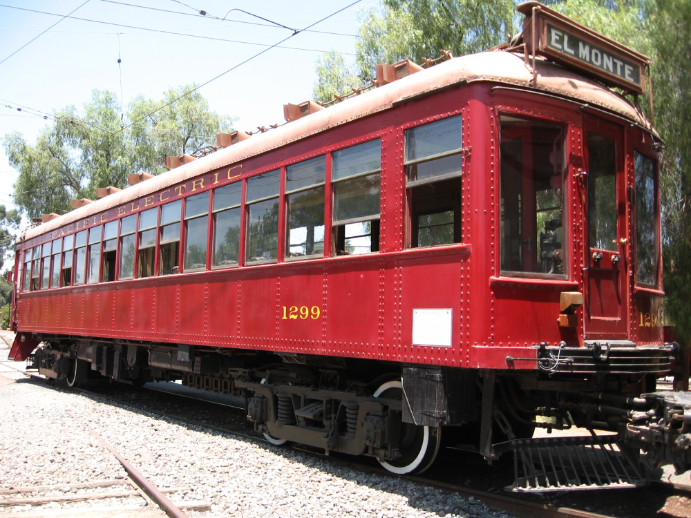 A red Pacific Electric vintage railway car numbered 1299, with a destination sign reading “EL MONTE” on the roof.