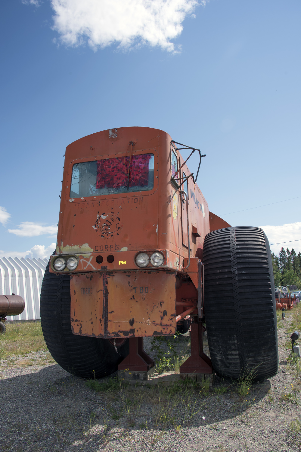 A weathered, orange, heavy-duty off-road vehicle with large black tires on display outdoors.