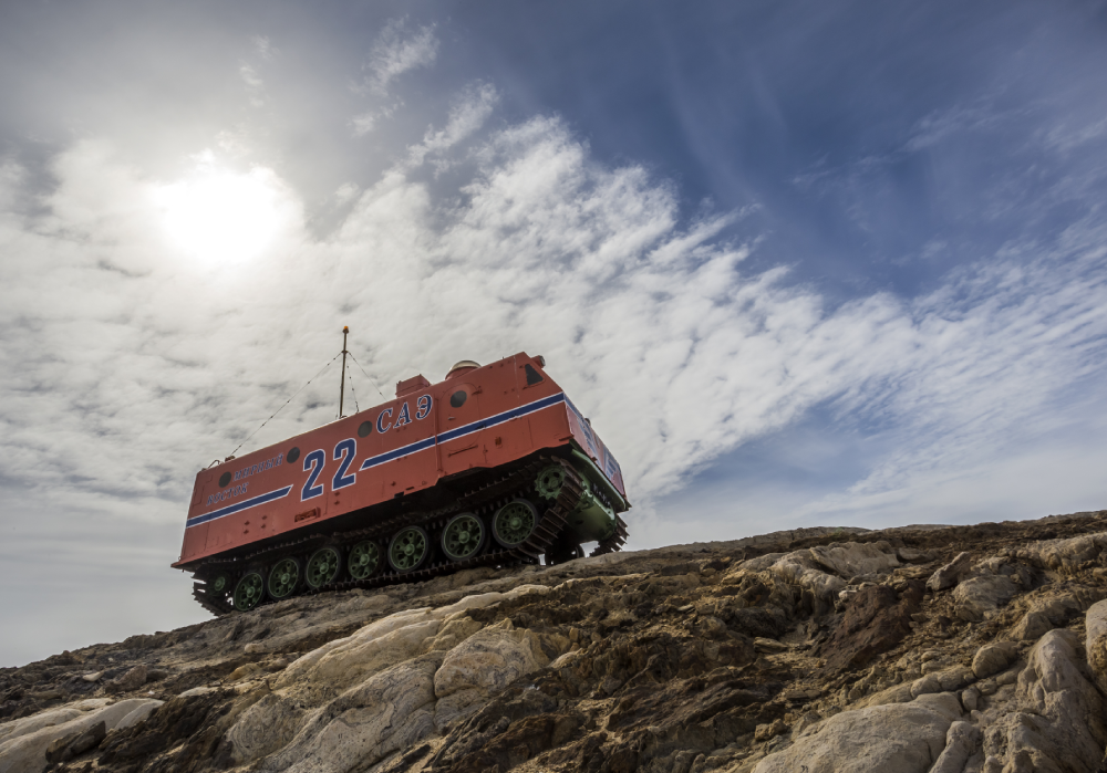 A red, tracked all-terrain vehicle numbered 22 and CA9 parked on a rocky slope under a bright sky.