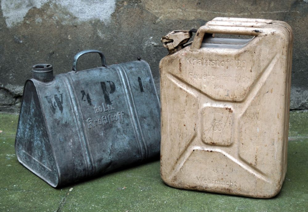 A triangular metal fuel can labeled “W P 1” next to a rectangular tan metal jerrycan stamped “Kraftstoff 20” and “Wehrmacht.”
