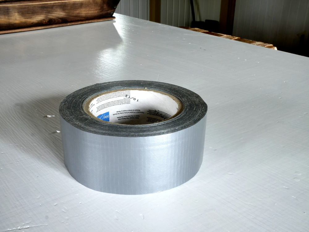 A roll of silver duct tape sitting on a white painted surface.