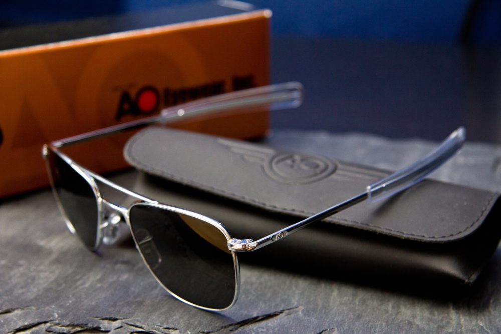 Silver-framed aviator sunglasses with a matching leather case and branded box.