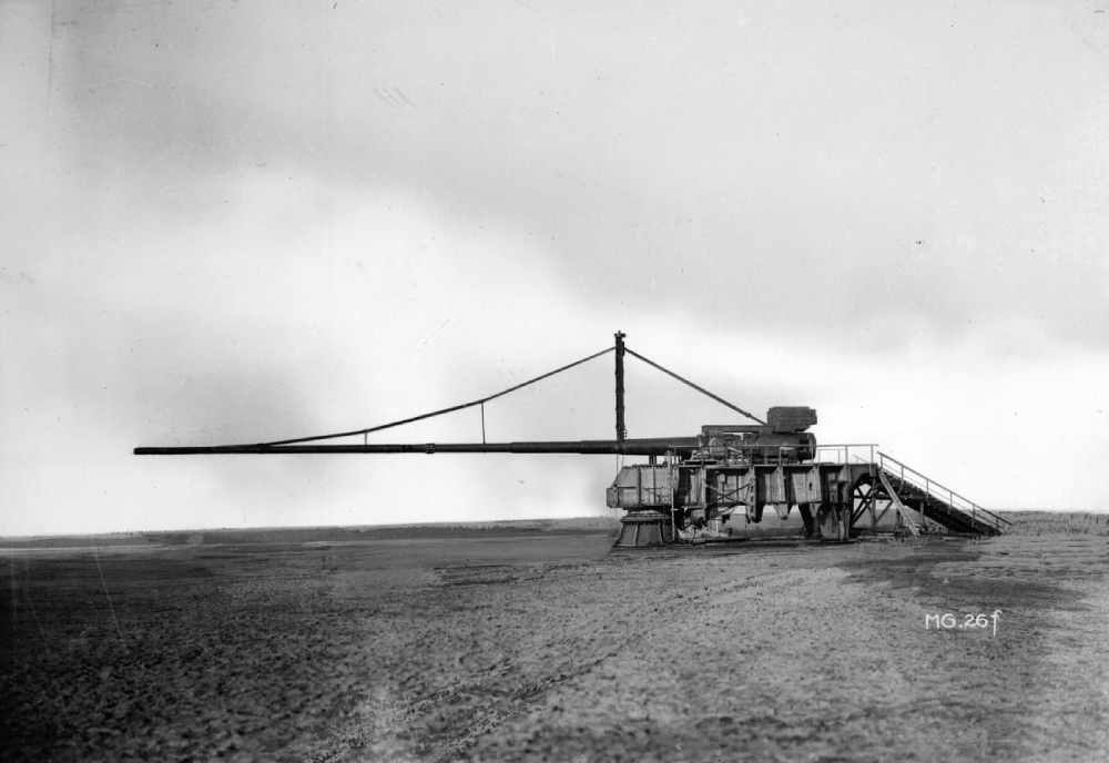 A large, long-barreled artillery piece mounted on a heavy metal carriage in an open field.
